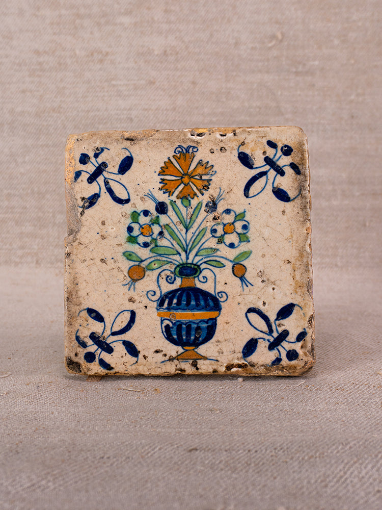 Square hand-painted French faience tile with blue vase, polychrome flowers, and floral motifs on beige.