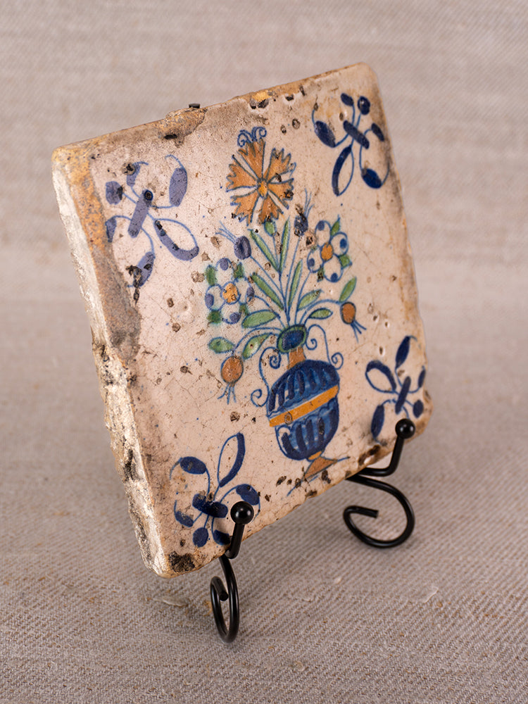 Antique French faience tile from Provence with hand-painted polychrome flower vase, on black metal stand.