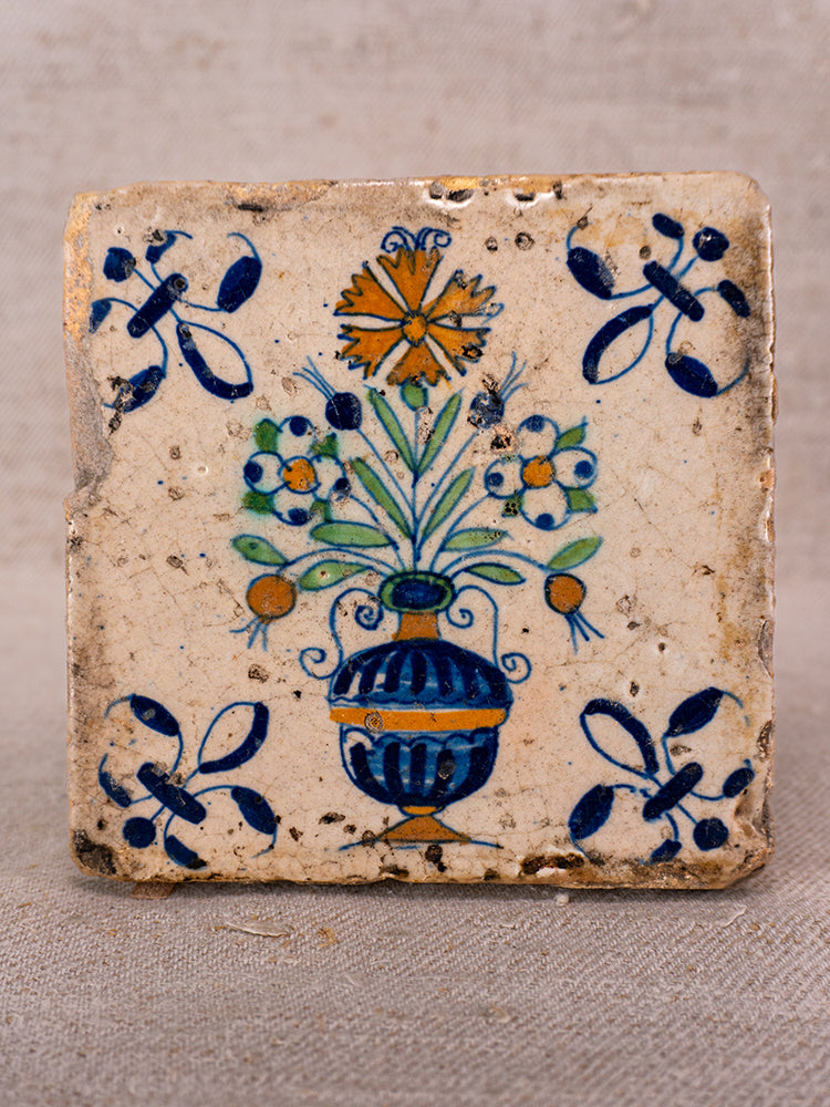 Antique French faience tile with hand-painted blue vase, polychrome flowers, and classic Provence motifs.