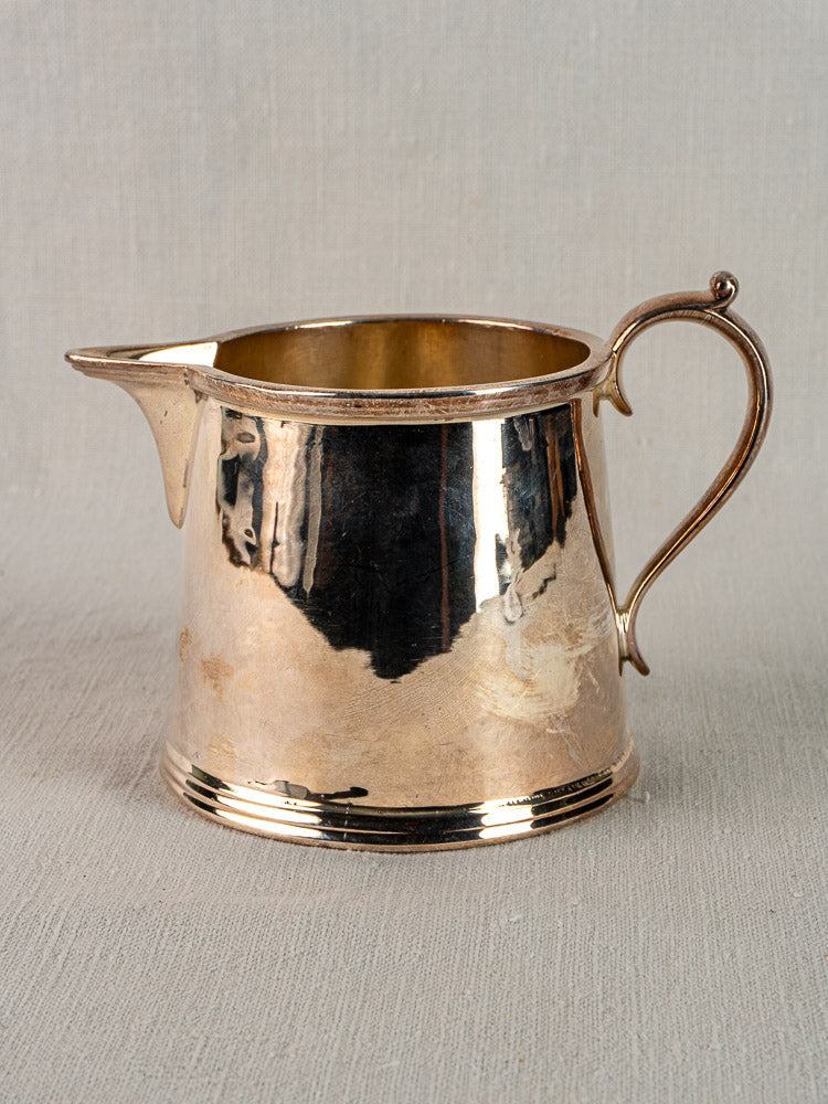 Antique English silver plate milk jug by Walker & Hall, circa 1900, with curved handle and reflective polished surface.