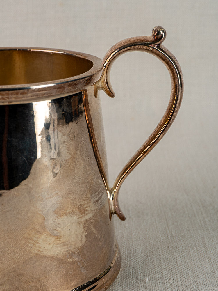 Antique English silver plate milk jug by Walker & Hall, tarnished with patina and a curved handle on a light background.