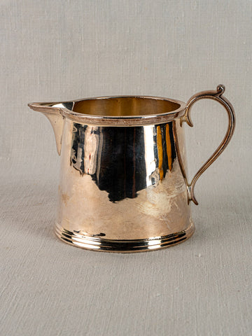 Antique English silver plate milk jug by Walker & Hall, c. 1900, curved handle, on textured light grey background.