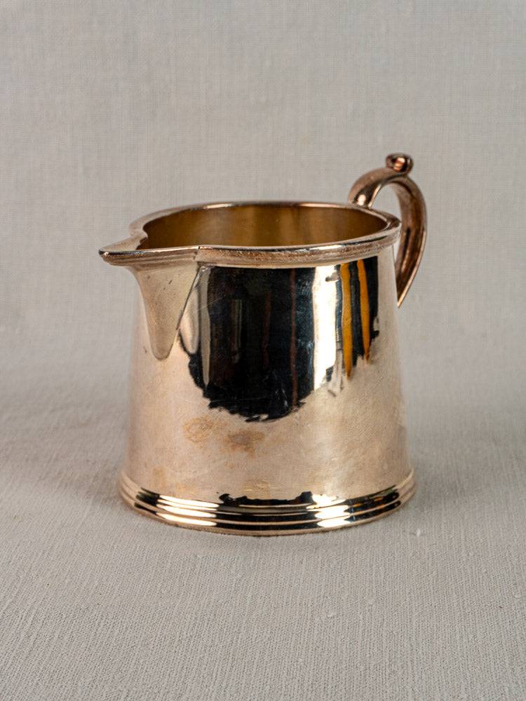 Antique English silver plate milk jug by Walker & Hall, Sheffield, circa 1900, on light gray textured surface.