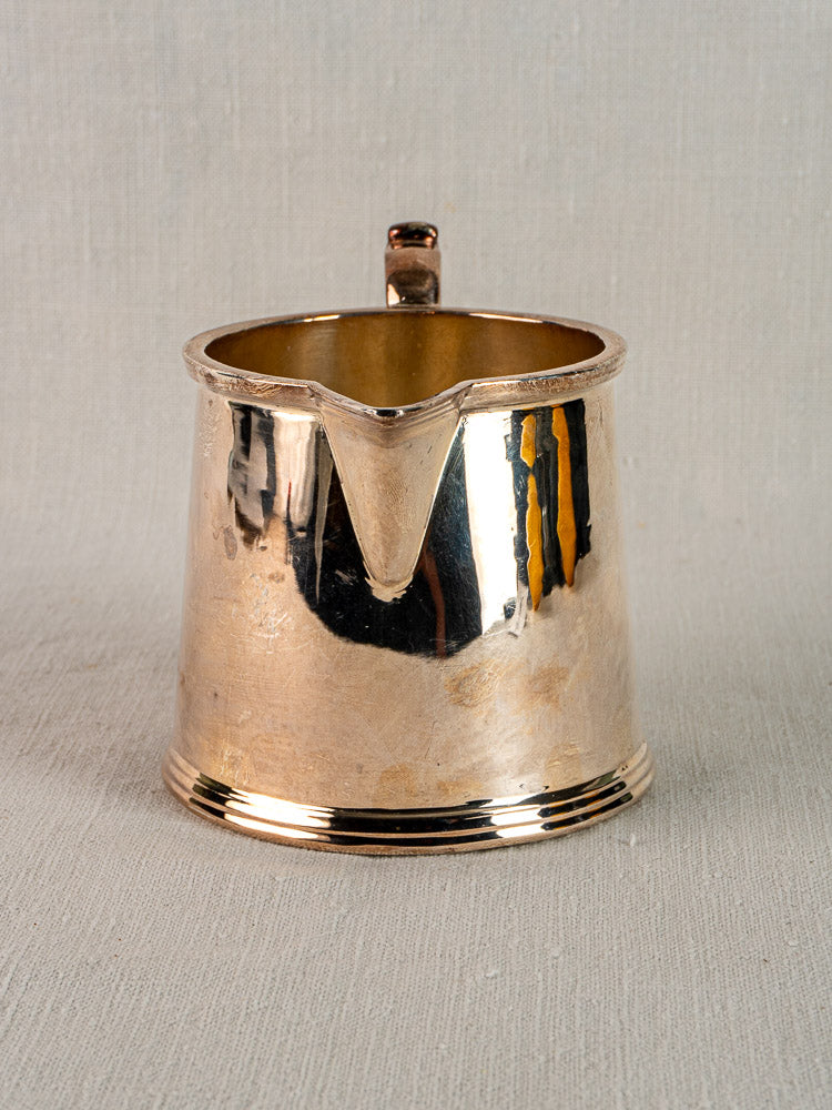 Antique English silver plate milk jug by Walker & Hall, wide spout, ridged base, on neutral fabric background.