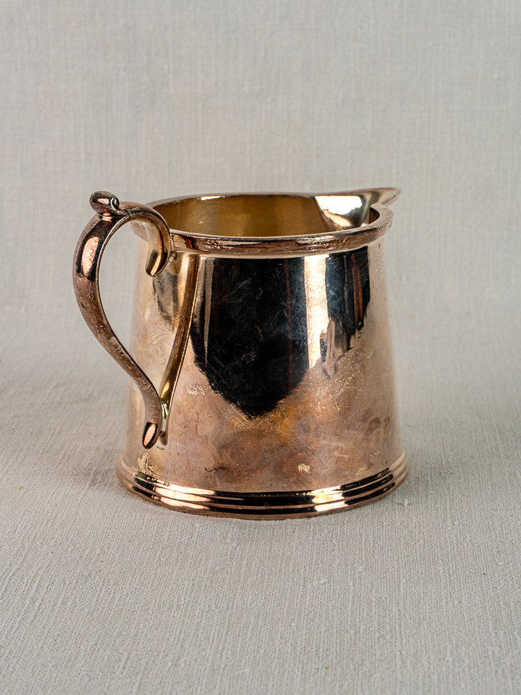 Antique English silver plate milk jug by Walker & Hall, Sheffield, c.1900, with curved handle on light textured fabric.