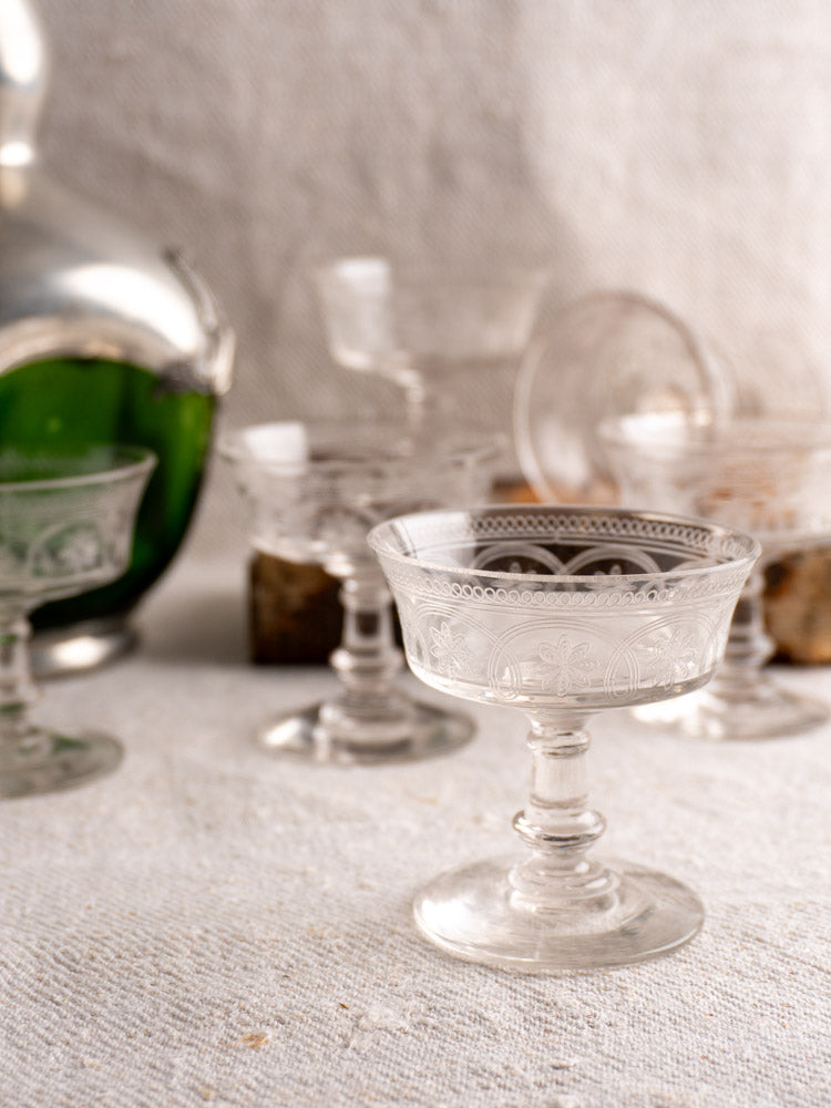 Set of six antique French uranium glass coupes from circa 1900, glowing green against black background.