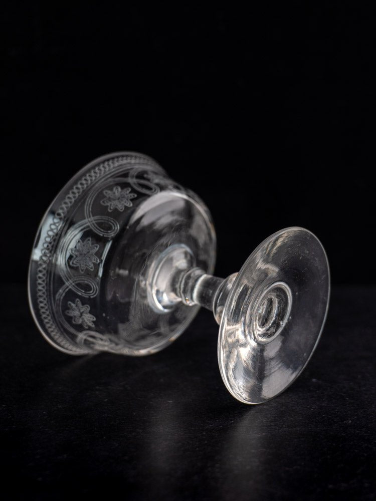 Clear glass French uranium dessert cup, circa 1900, with ornate engraved design on black background.