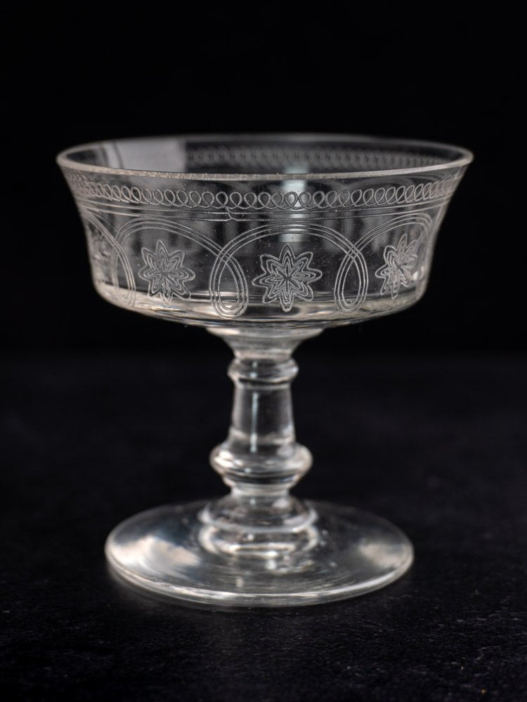 Set of six antique French uranium glass coupes with etched floral and geometric patterns, black background.