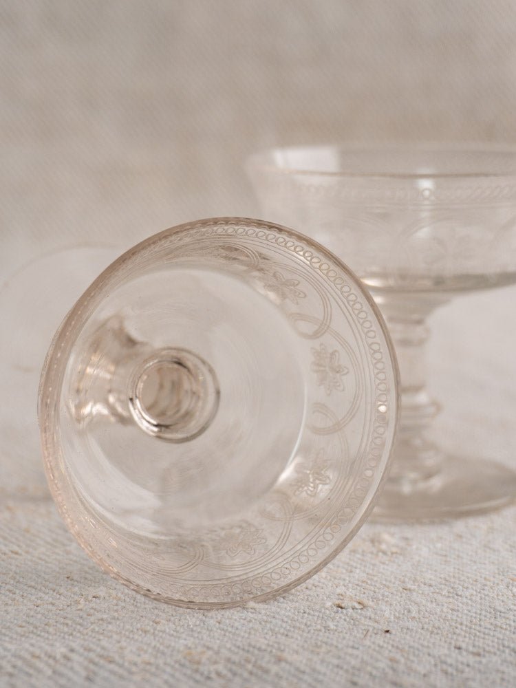 Set of six antique French uranium glass coupes, circa 1900, on a neutral textured surface.