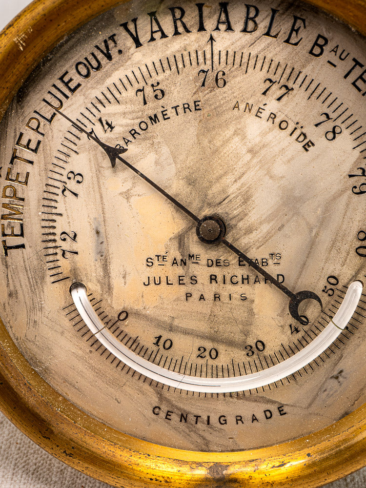 Antique French barometer by Jules Richard, Paris, early 20th century brass case, aged dial with visible wear.