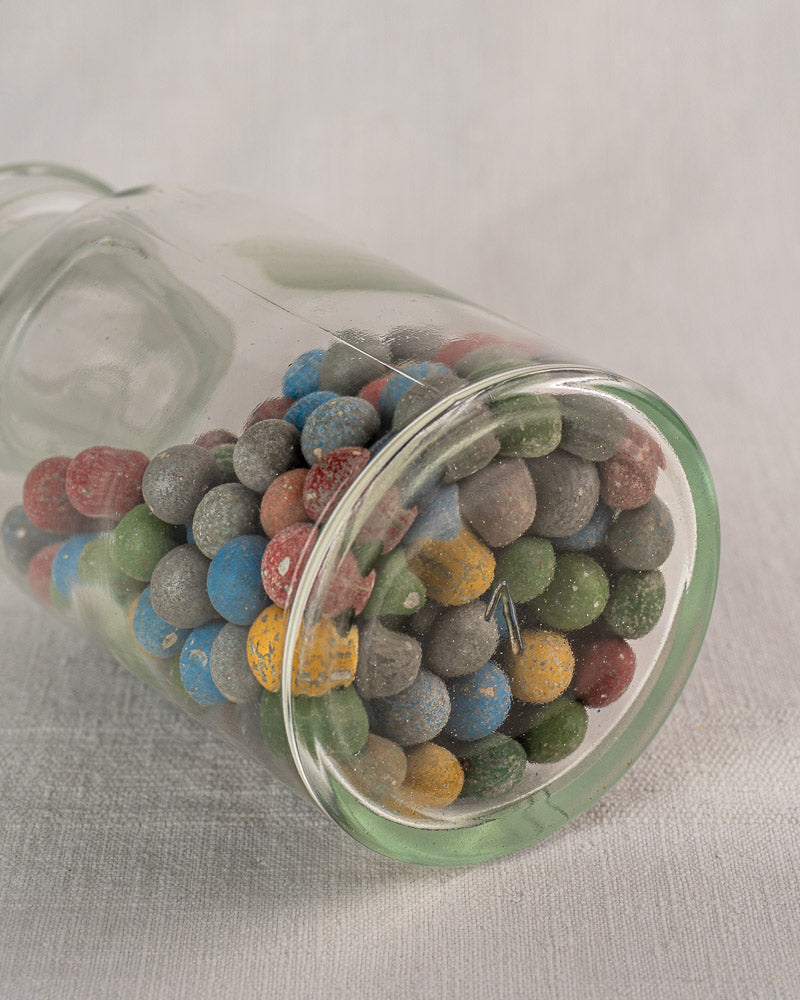 Antique French apothecary jar from the Clay Marble Collection, circa 1900, filled with colorful candy on light fabric.