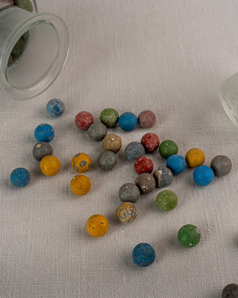 Pair of antique French apothecary jars, circa 1900, on beige fabric with colorful candies scattered beside them.