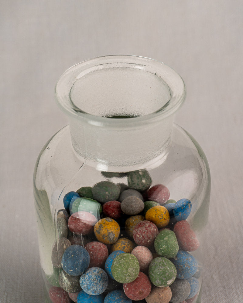 Antique French apothecary jar circa 1900 with colorful clay marbles inside, viewed from above.