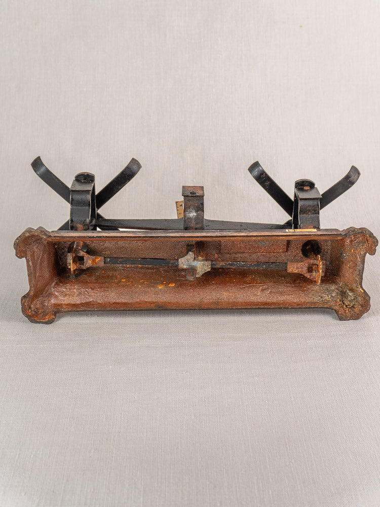 Antique French cast iron and brass Roberval balance scale with two black pans, plain light background.