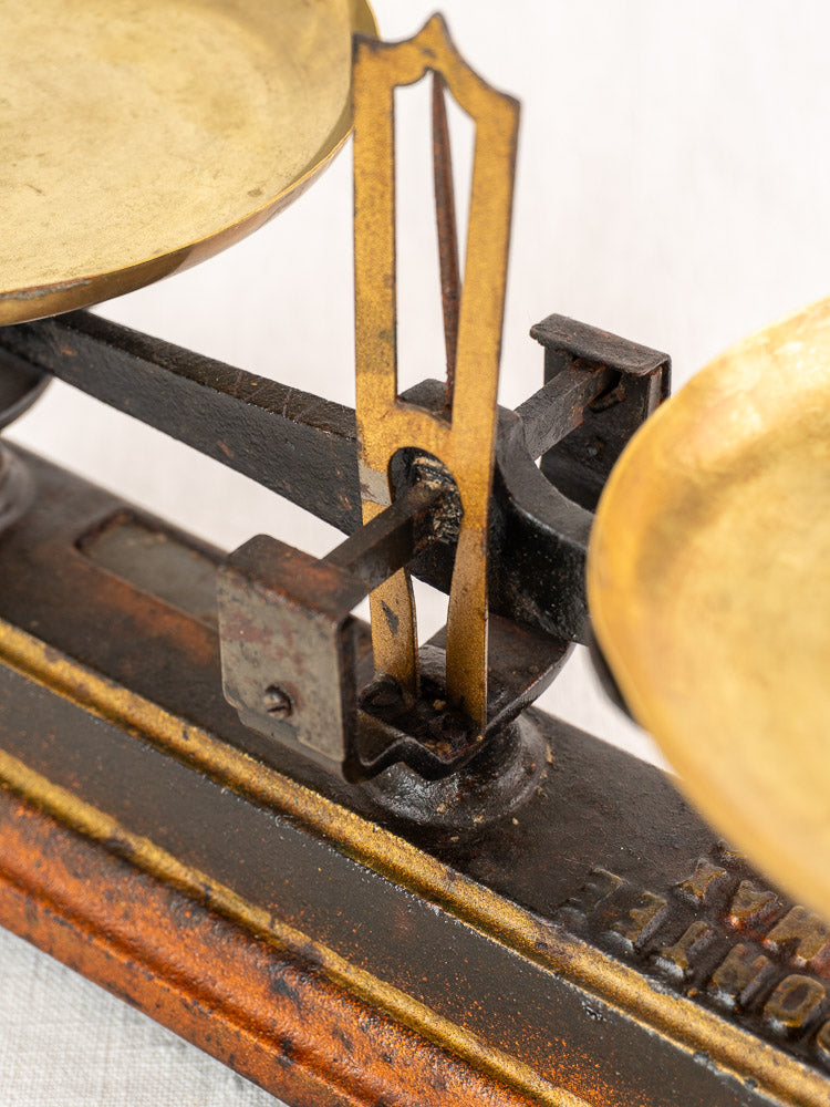 Antique French Roberval balance scale in cast iron and brass with two trays, central pointer, and weathered base.