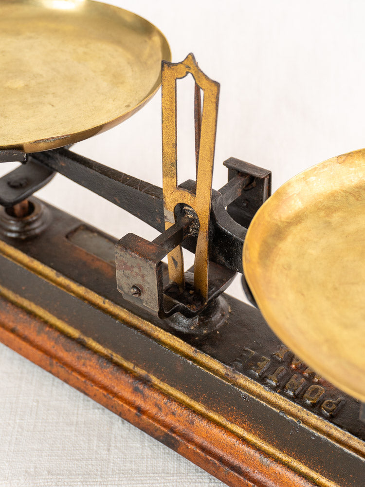 Antique French cast iron and brass Roberval balance scale with dual trays, central pointer, and classic wooden base.