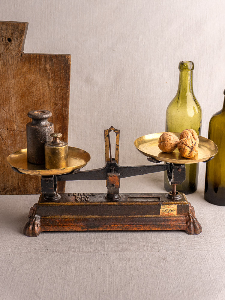 Antique French cast iron and brass Roberval balance scale with weights on one side, walnuts on the other.