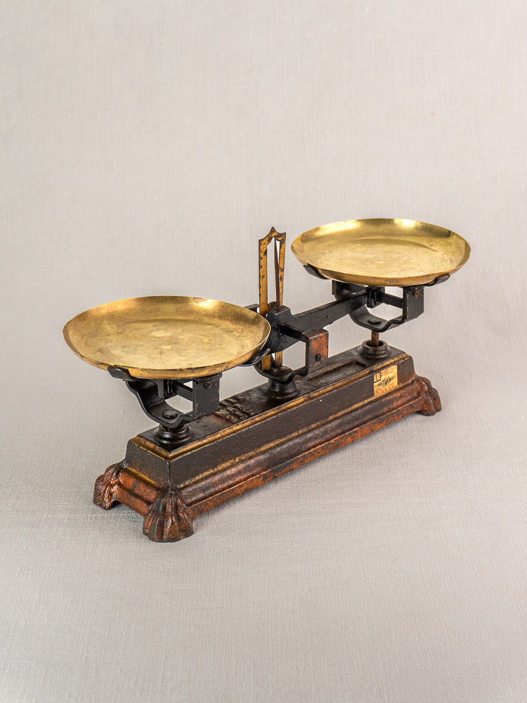 Antique French balance scale with cast iron base and two brass pans, ornate Roberval Force 5 Kg detailing.
