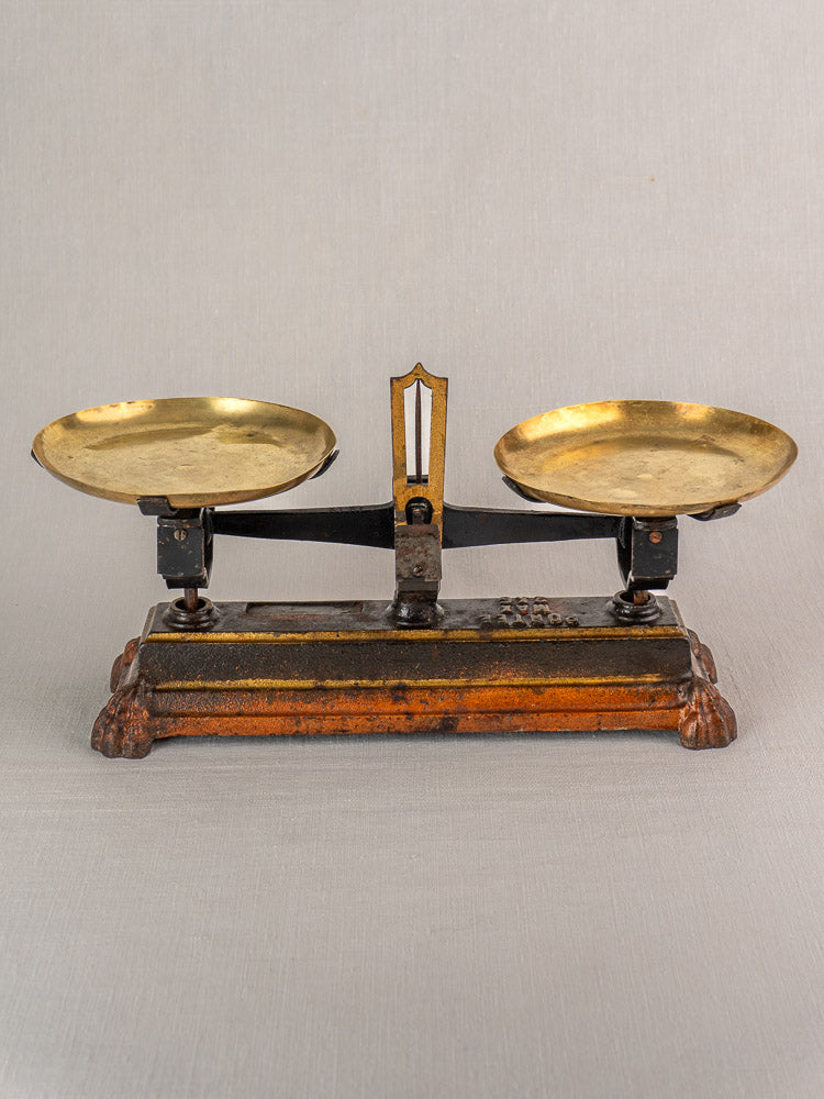 Antique French Roberval Force 5 kg balance scale with cast iron, brass plates, ornate brown-and-gold base on gray background.