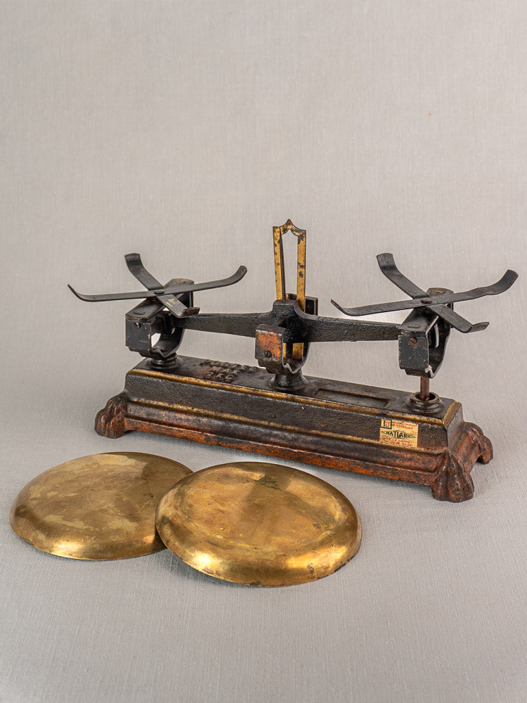Antique French Roberval balance scale in cast iron and brass with ornate black and gold details; plates placed in front.