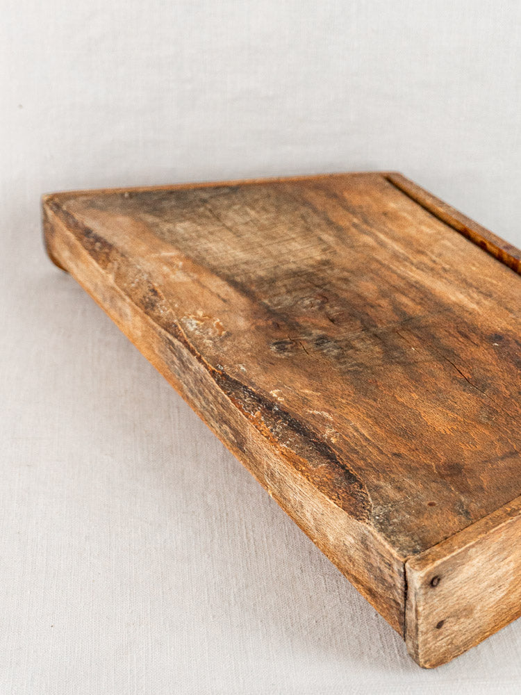 Antique French beech cutting board, late 19th century, on a light fabric surface.