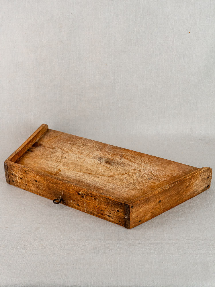 Antique French beech gallery cutting board, late 19th century, on light gray fabric background.