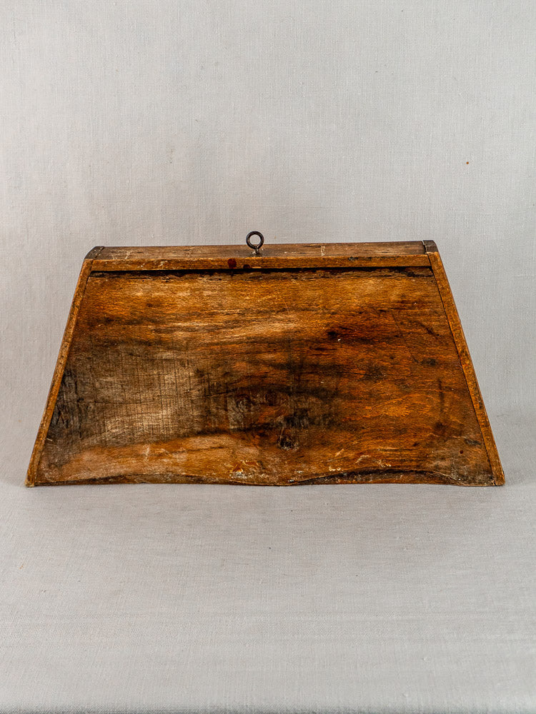 Late 19th-century French beech cutting board with trapezoid shape and metal hook, on light gray background.