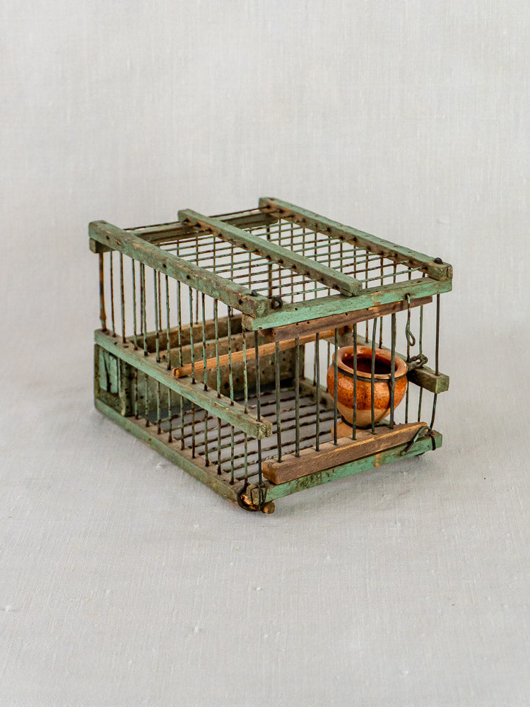 Antique French sage green decoy bird cage in weathered wood and metal with suspended clay pot.