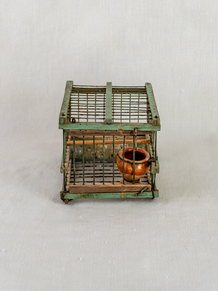 Antique French sage green decoy bird cage with weathered metal and wood frame, tiny clay pot inside.