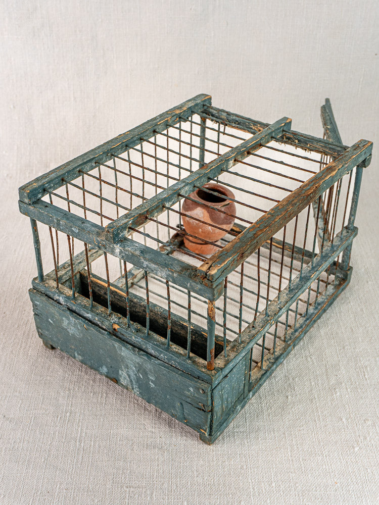 Late 19th-century Provence bird cage with weathered blue paint and terracotta cup, rectangular frame, antique accent.