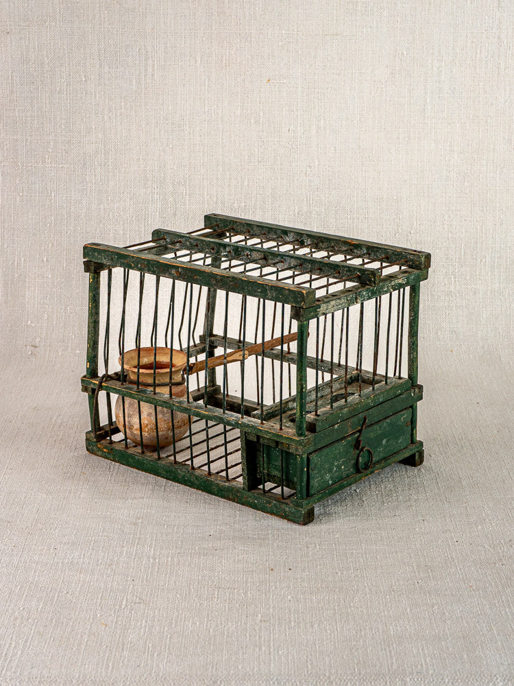 Antique French bird cage circa 1900 with green frame, vertical bars, wooden perch, and original terracotta feeder.