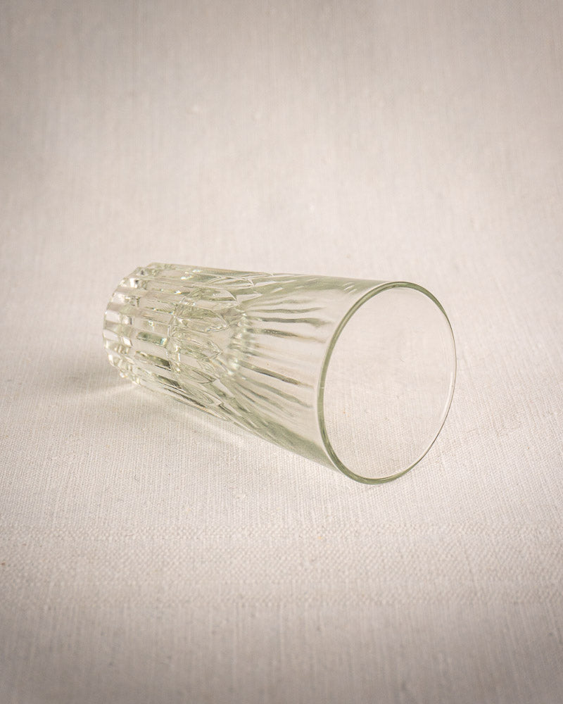 Vintage French bistro wrought iron and rattan glass caddy with six fluted tumblers on a light fabric surface.