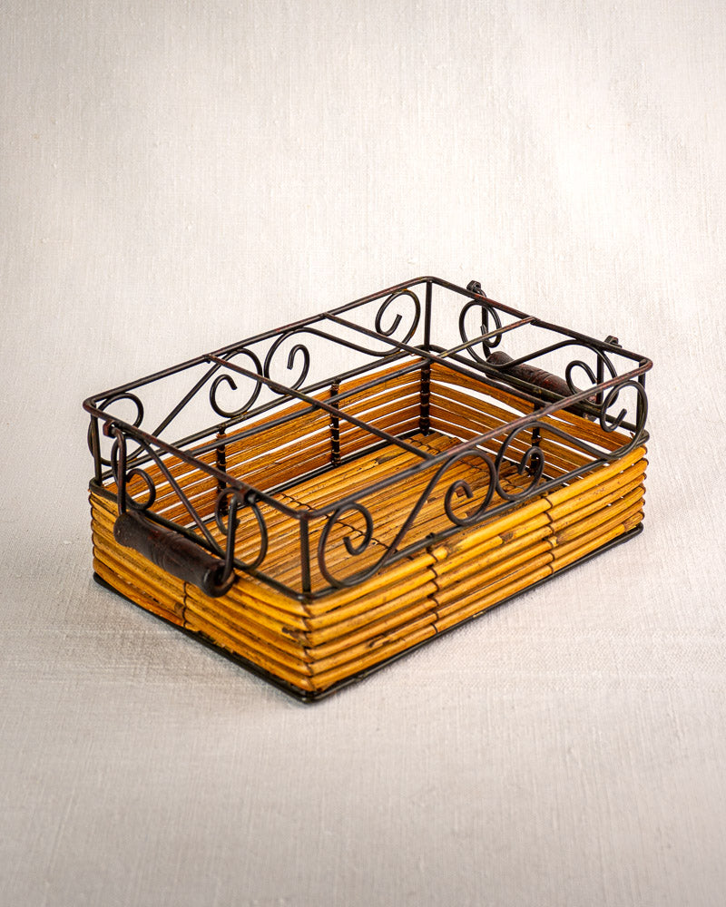 Vintage French bistro glass caddy with wrought iron scrollwork and rattan, holds six fluted tumblers on a light textured surface.