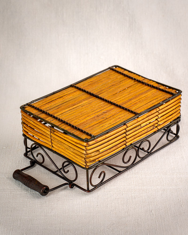 Vintage French bistro glass caddy in wrought iron and rattan with six fluted tumblers on neutral fabric surface.