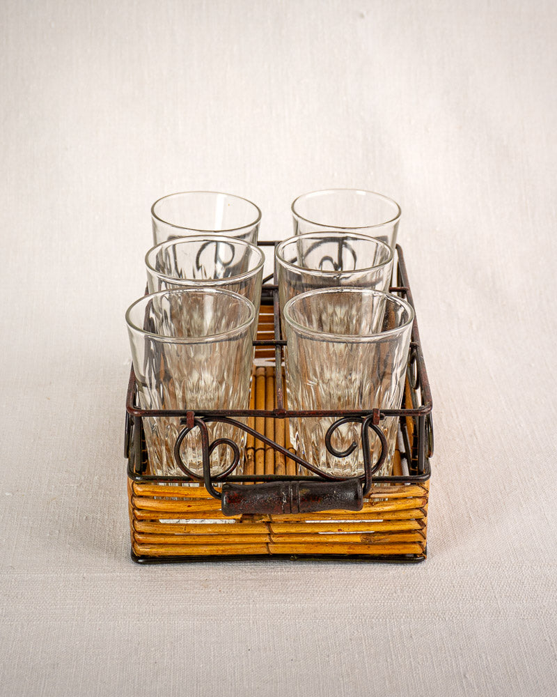 Set of six fluted tumblers in a vintage French bistro glass caddy with wrought iron and rattan handle.