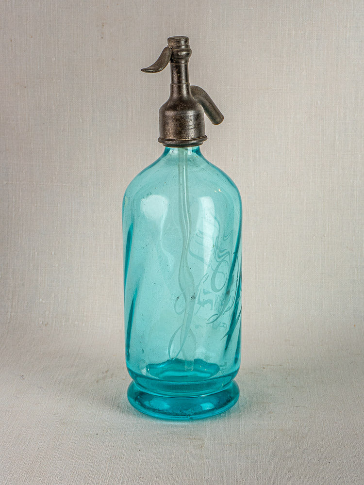Antique French bistro soda siphon with vintage blue glass and metal top on neutral background.