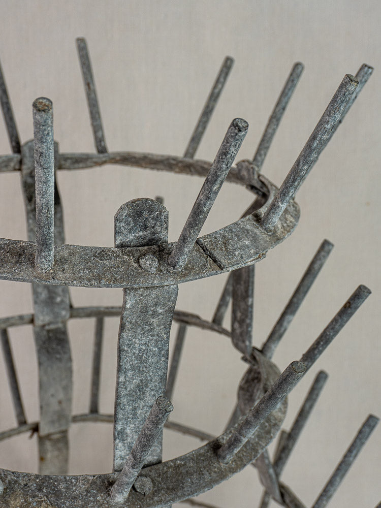 Antique French bottle dryer, c.1900, galvanized zinc with circular four-tiered pronged design on a plain light background.
