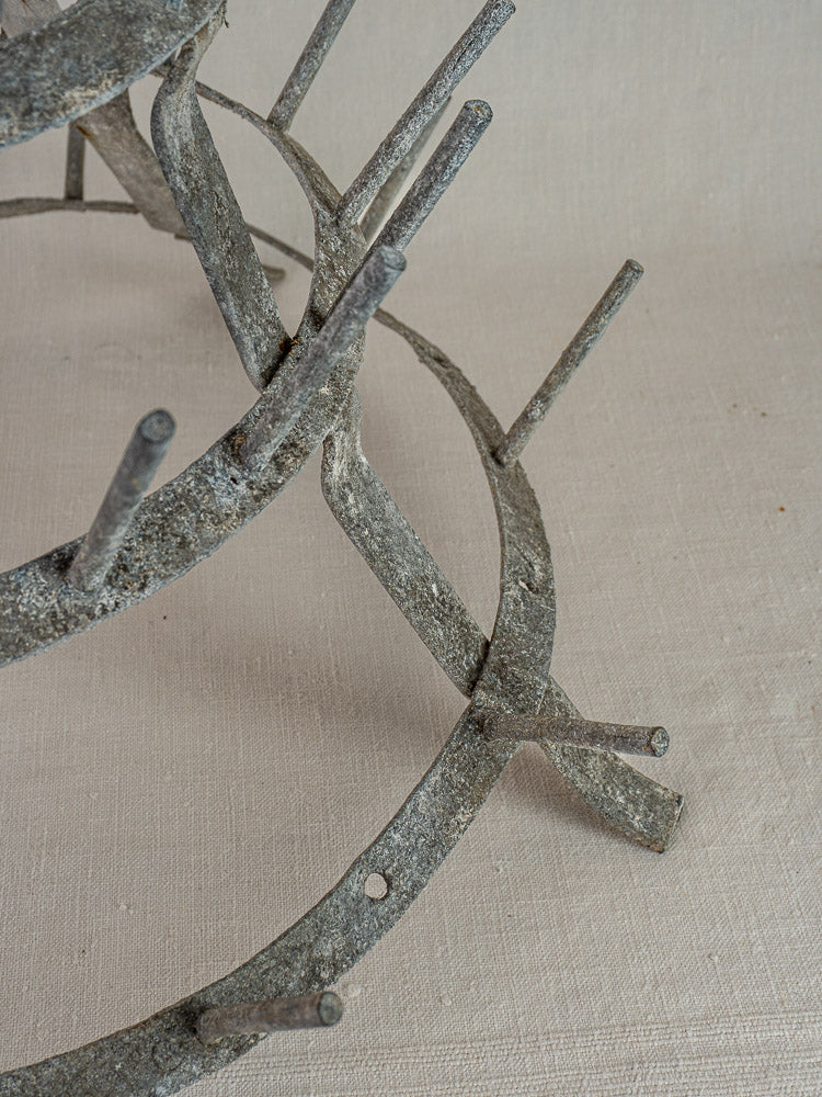 Antique French bottle dryer, circa 1900, weathered galvanized zinc with multiple prongs on light textured fabric surface.