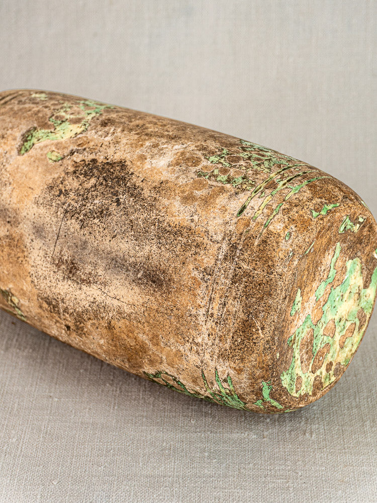 Antique French terracotta Bouillotte, 18th century, cylindrical and weathered with green oxidation on brown, on textured backdrop.