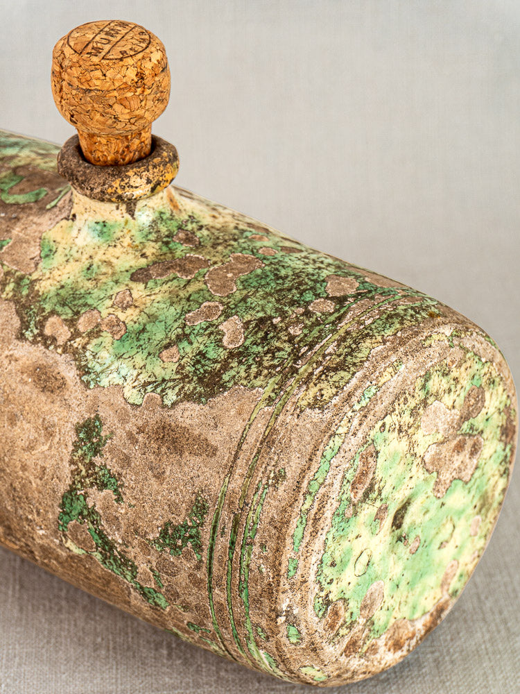 Antique French 18th-century terracotta bouillotte with cork stopper and green-beige patina on plain neutral background.