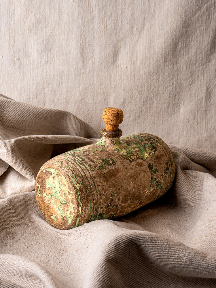 Antique 18th-century French terracotta Bouillotte with cork stopper and rich patina on beige fabric backdrop.