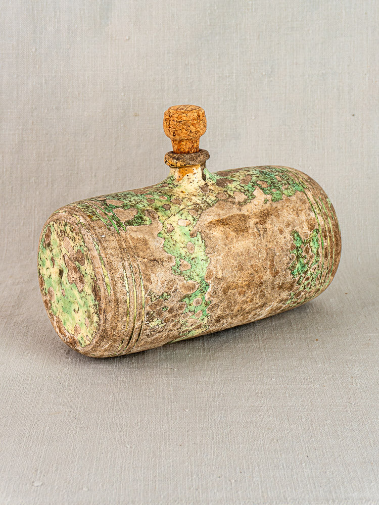 Antique French terracotta bouillotte with green and brown patina, small cork stopper, on light gray textured surface.