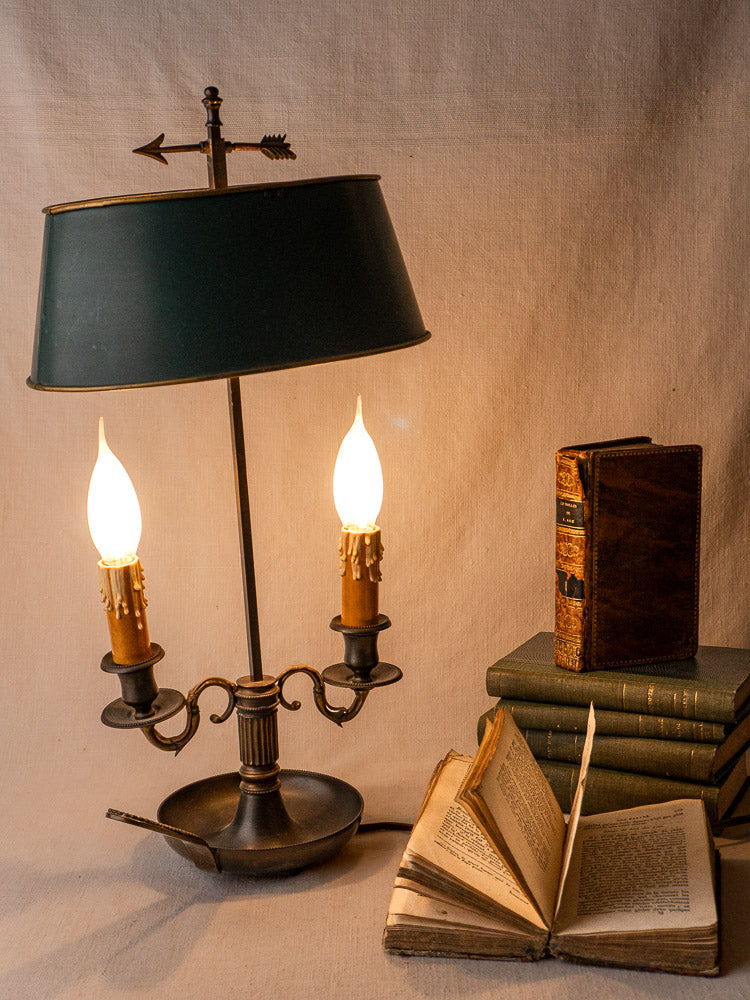 French Bouillotte lamp with vintage green tôle shade in Louis XVI style beside old books.
