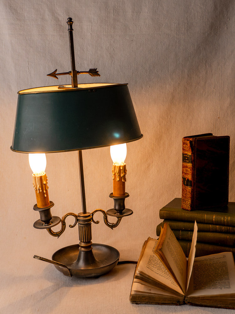 French Bouillotte lamp with vintage green tôle shade and Louis XVI details beside antique books.