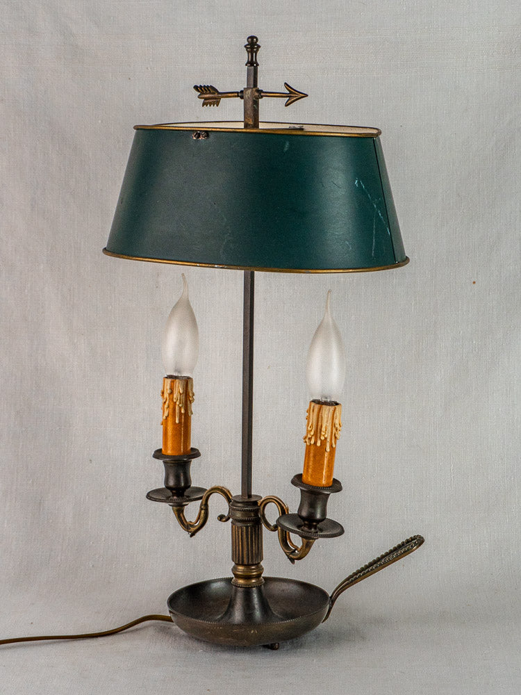 Antique French Bouillotte lamp with green tôle shade, brass accents, and arrow finial on white background.
