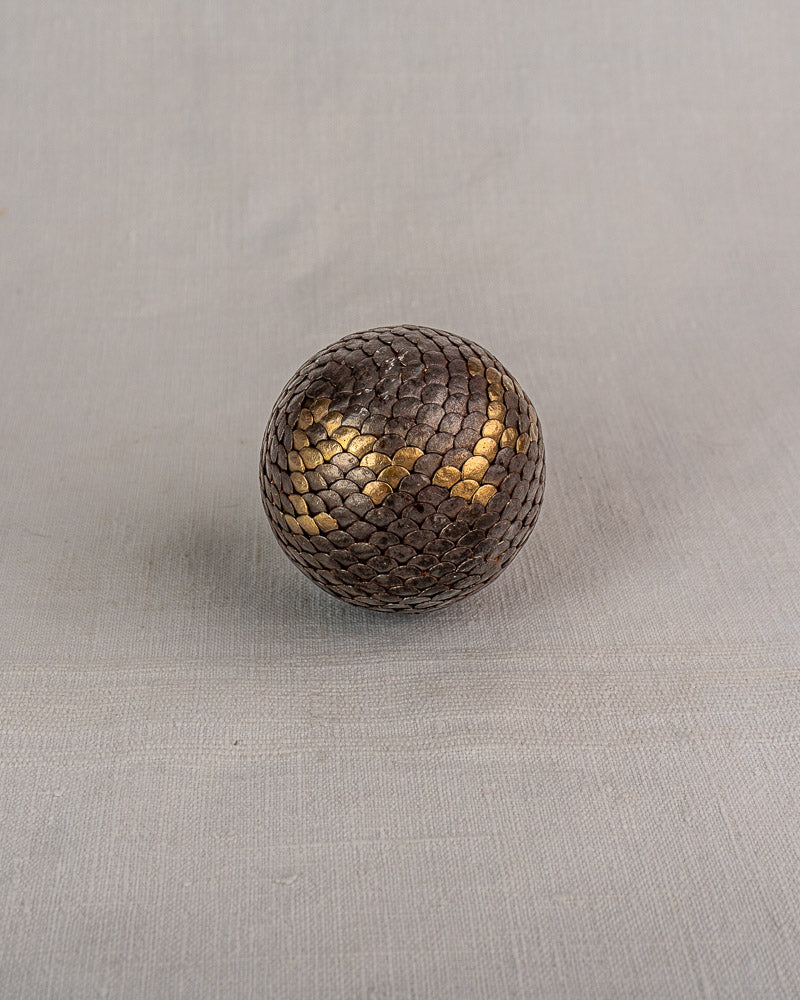 Set of five antique French Petanque balls with brown and gold scales on light gray fabric background.