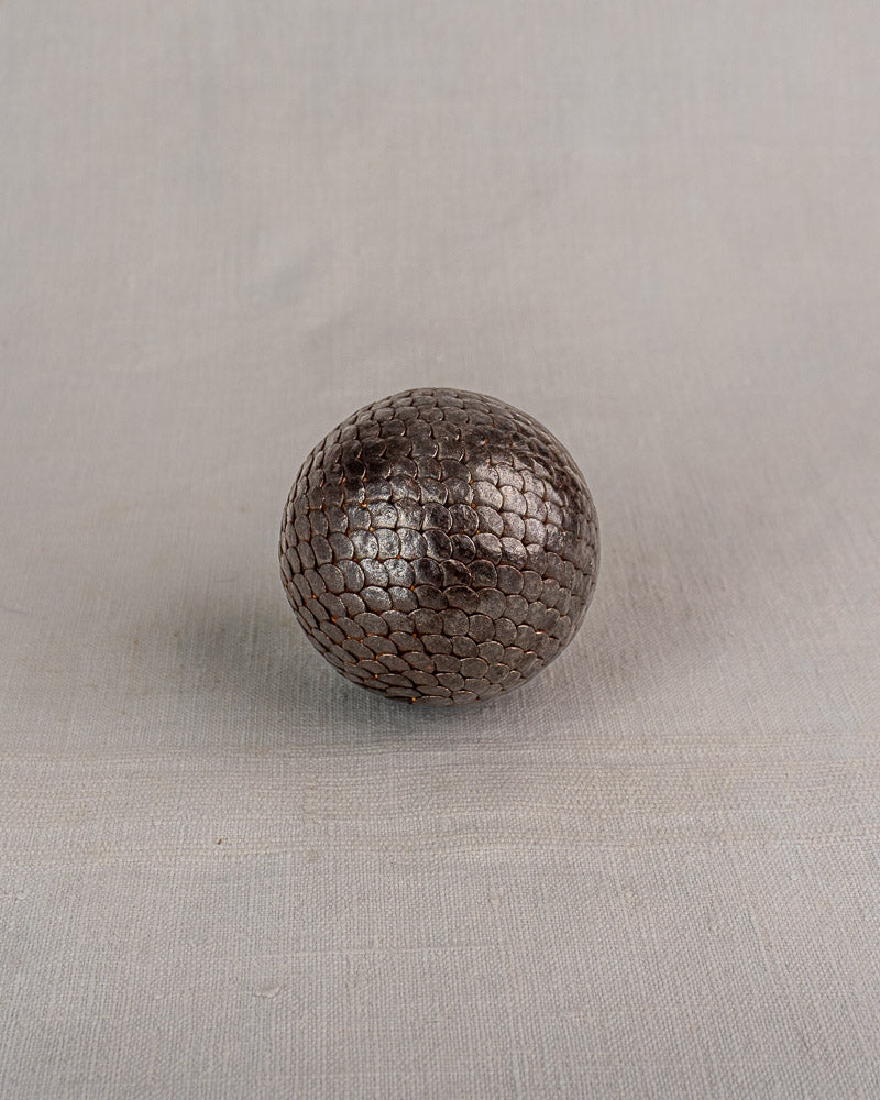 Set of five early 20th-century antique French petanque balls in dark brown textured leather on light gray fabric.