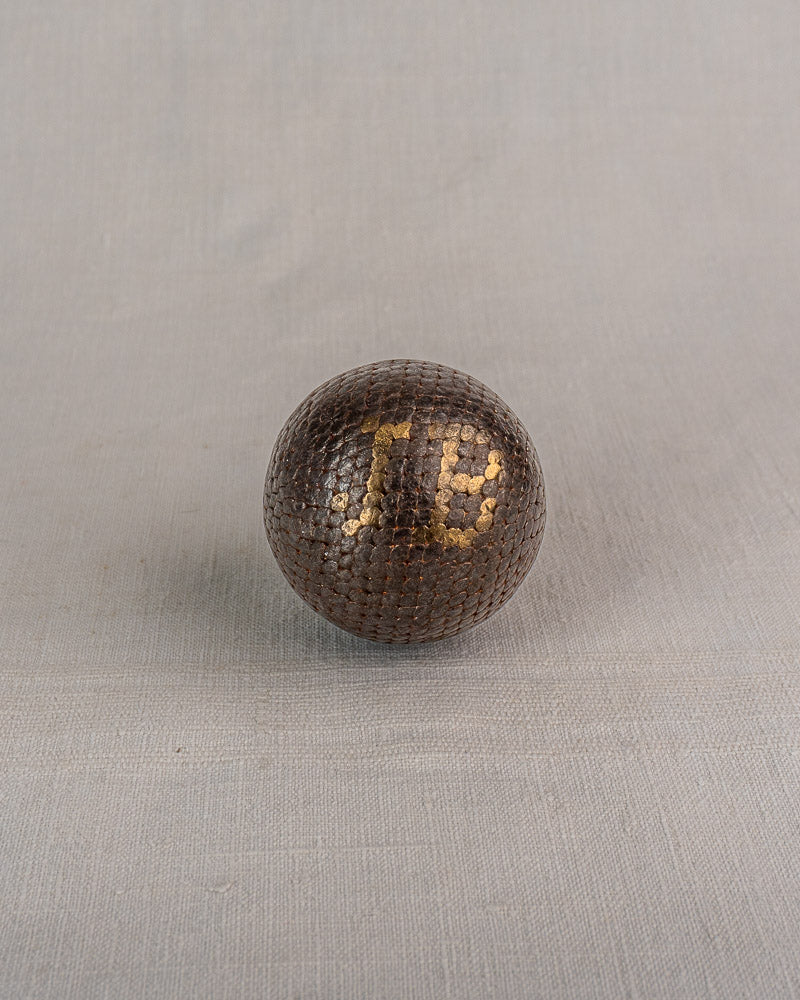 Set of five early 20th-century antique French Petanque balls with dark and gold hexagonal scales on gray textured surface.