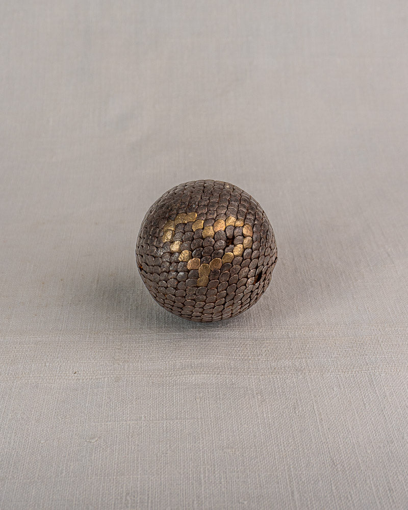 Set of five early 20th-century antique French Petanque balls with dark brown and gold metallic cloutées accents on gray surface.