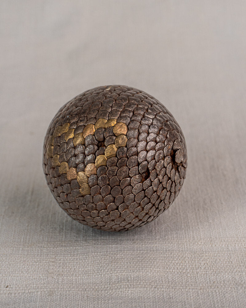 Set of five early 20th-century French Petanque balls with brown, scale-like patterns and gold accents on light gray surface.